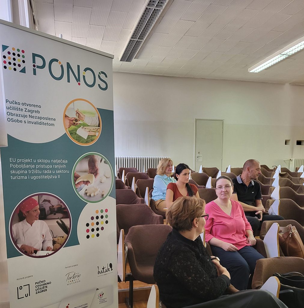 Rollup plakat PONOS u konferencijskoj dvorani. Uz njega sjede uzvanici konferencije, dvije gospođe s naočalama i dvije gospođe i gospodin u zadnjim redovima.